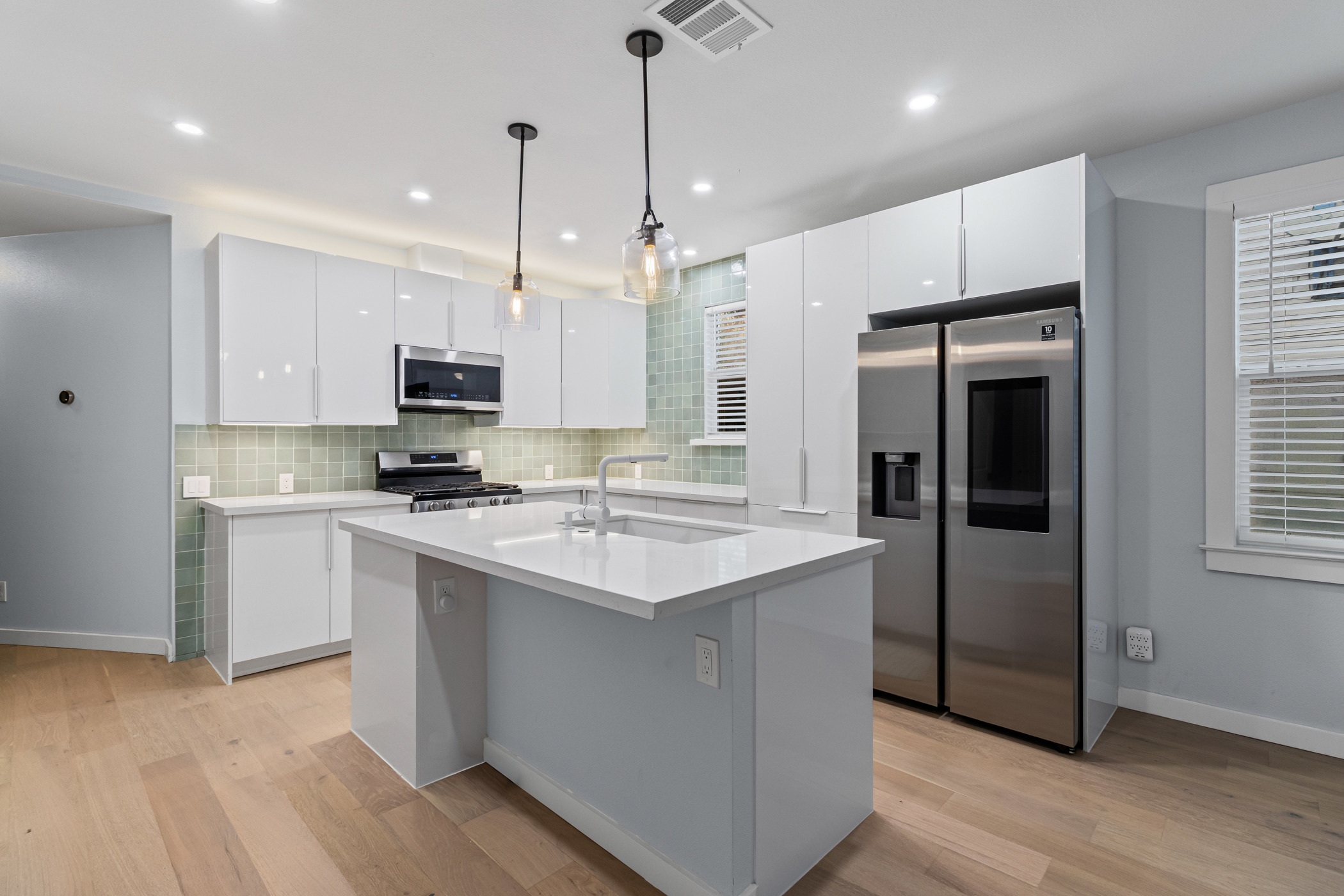 84 Waller Street Austin, TX 78702 - Photo 6 of 22 Kitchen with white cabinets, appliances with stainless steel finishes, pendant lighting, an island with sink, and recessed lighting