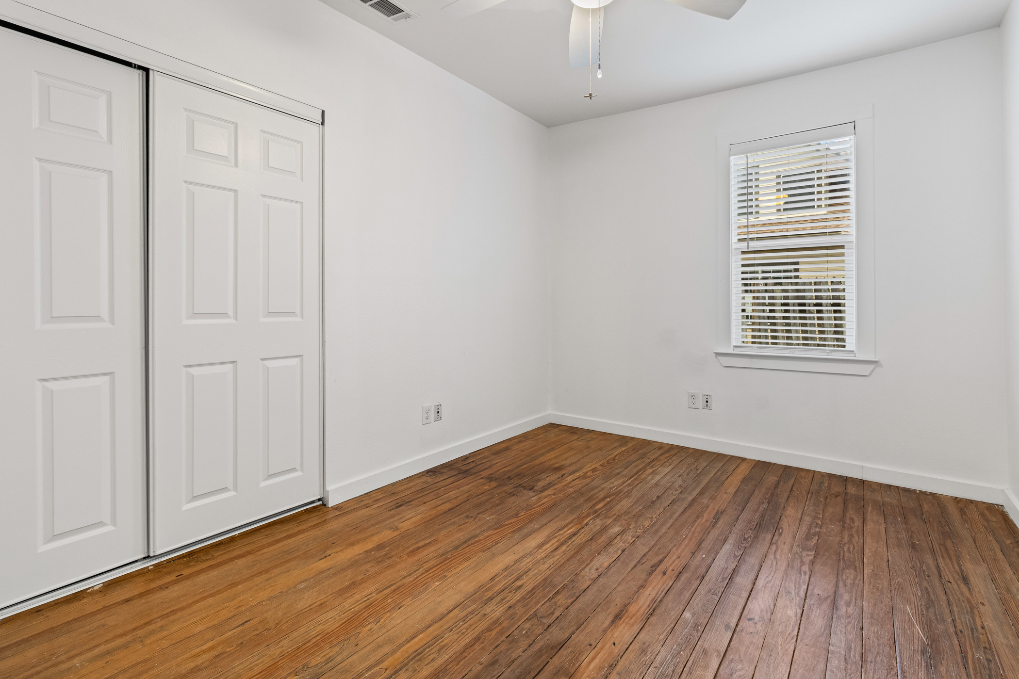 84 Waller Street Austin, TX 78702 - Photo 10 of 22 Unfurnished bedroom featuring wood-type flooring, ceiling fan, and a closet