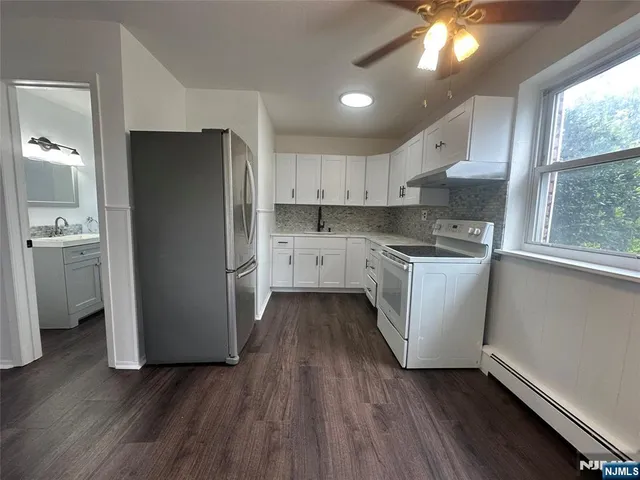a kitchen with a refrigerator a sink and wooden floor