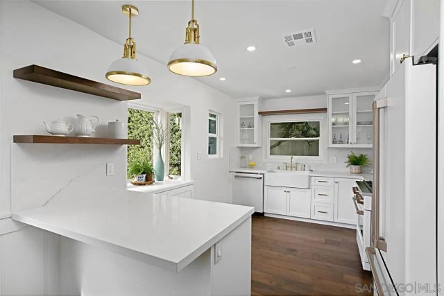 a kitchen with white cabinets and wooden floor