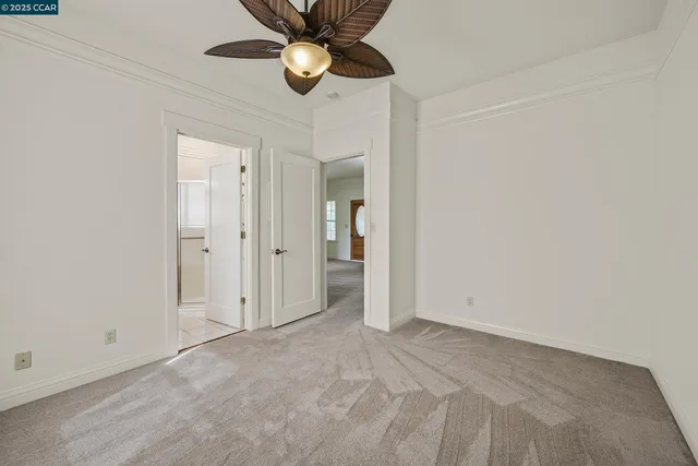 an empty room with a chandelier fan and closet