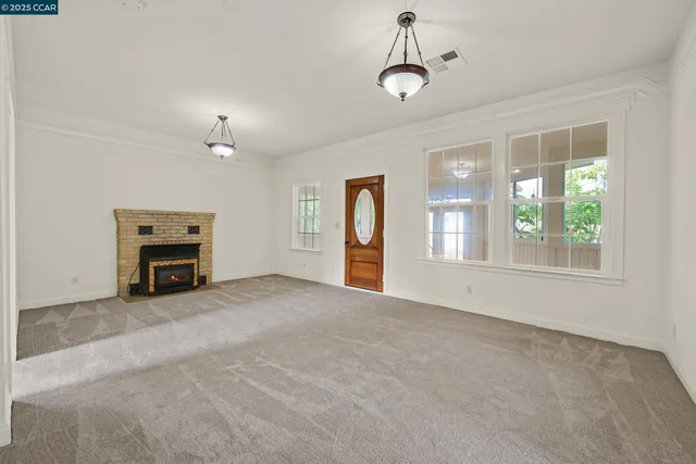 an empty room with windows and fireplace