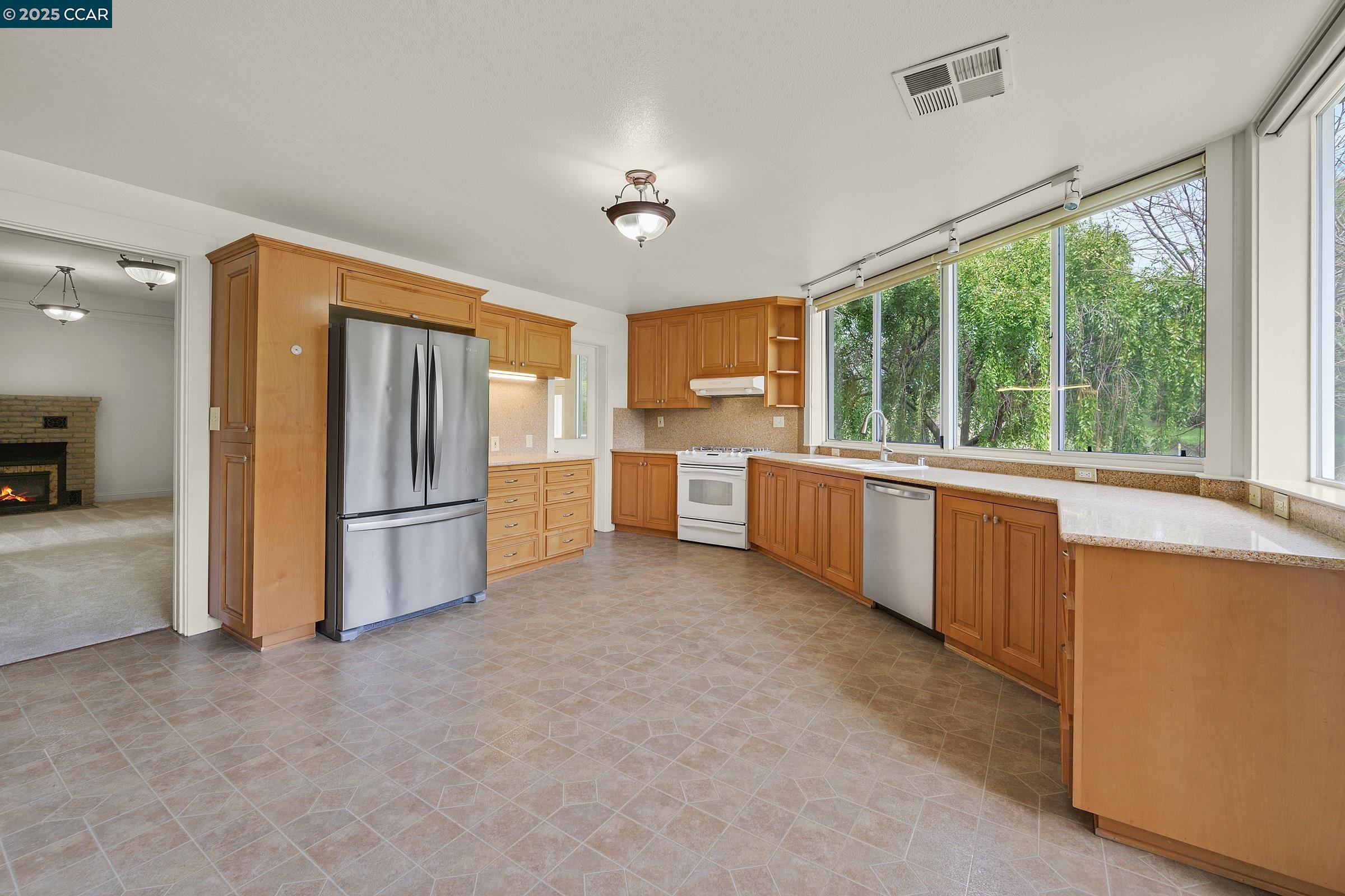 2581 Charles Avenue Pinole, CA 94564 - Photo 16 of 50 a kitchen with stainless steel appliances granite countertop a refrigerator a sink dishwasher a stove and a dining table with wooden floor