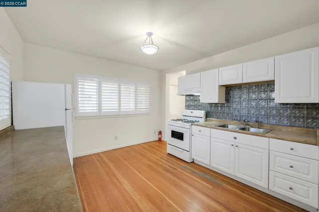 a large white kitchen with a large window a sink and stainless steel appliances