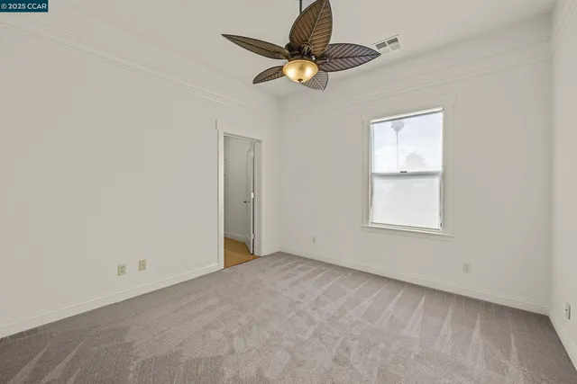 an empty room with a window and a fan