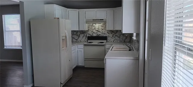 a kitchen with a refrigerator and white cabinets