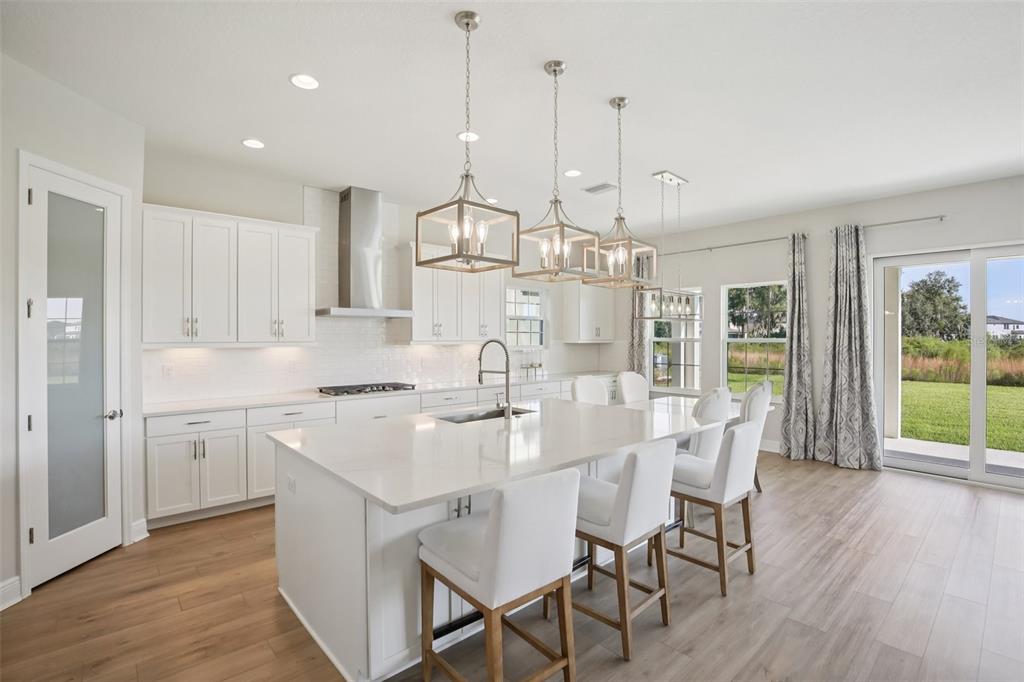 14930 Rider Pass Drive Lithia, FL 33547 - Photo 11 of 63 a kitchen with stainless steel appliances kitchen island granite countertop a stove a refrigerator a kitchen island with a dining table and chairs