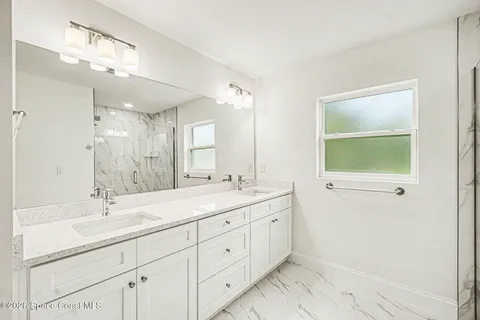 a bathroom with a double vanity sink a mirror and a bathtub