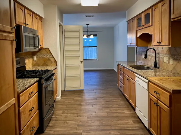 a kitchen with granite countertop a stove and a wooden floor