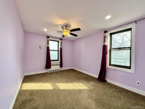 an empty room with windows and ceiling fan