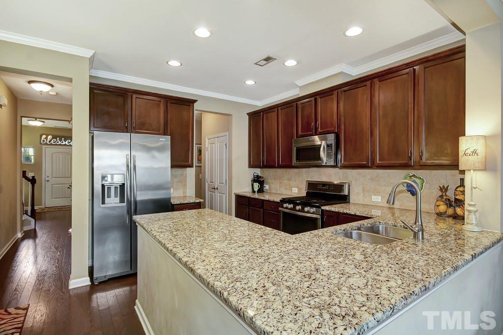 2456 Baslow Drive Apex, NC 27539 - Photo 11 of 39 a kitchen with granite countertop wooden cabinets a refrigerator and a sink