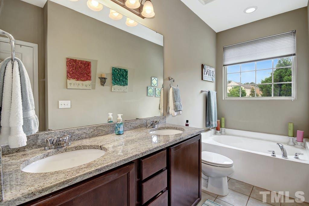 2456 Baslow Drive Apex, NC 27539 - Photo 16 of 39 a bathroom with a granite countertop sink and a mirror