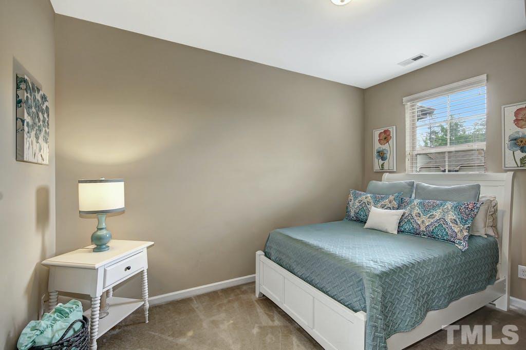 2456 Baslow Drive Apex, NC 27539 - Photo 18 of 39 a bedroom with a bed and a lamp on dresser