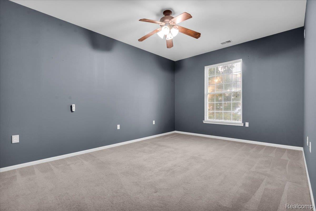 1150 Rial Lake Drive Howell, MI 48843 - Photo 15 of 24 Expansive room with carpet flooring, a multi-pane window, ceiling fan with integrated lighting, and neutral wall tones