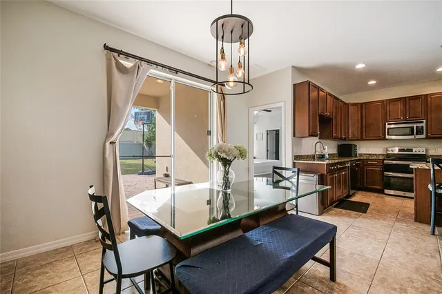 a living room with stainless steel appliances furniture a dining table and a chandelier