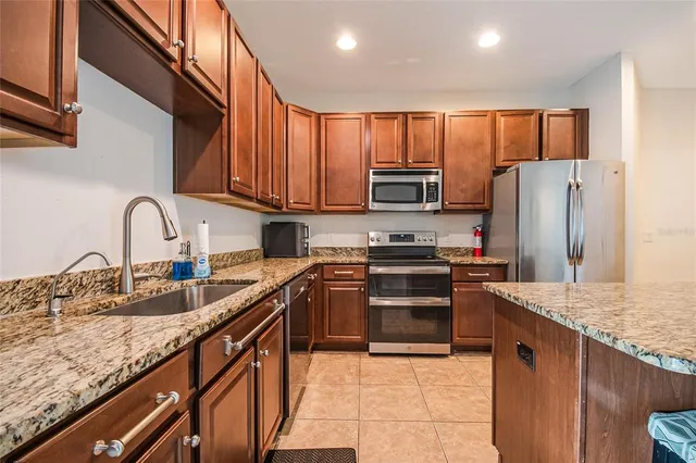 a kitchen with stainless steel appliances granite countertop a sink stove refrigerator and cabinets