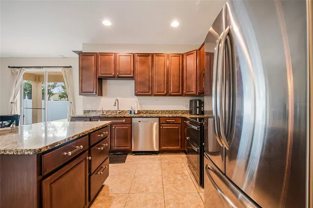 a kitchen with granite countertop a refrigerator stove top oven and sink