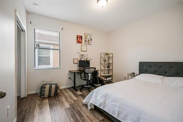 a bedroom with a bed a table and wooden floor
