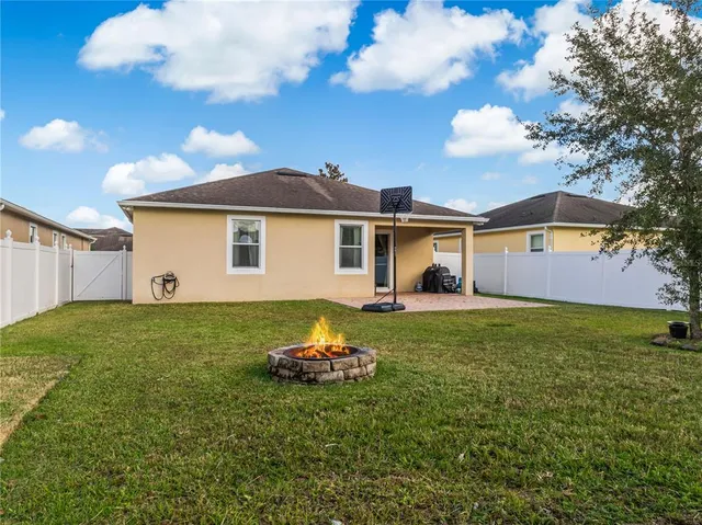 a backyard of a house with table and chairs plants and large tree
