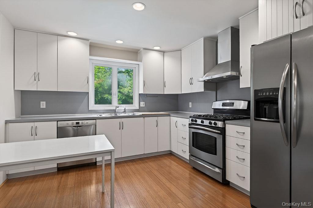 6 Winterberry Road Fishkill, NY 12524 - Photo 14 of 43 Kitchen featuring stainless steel appliances, wood-finish flooring, white cabinetry, a built-in dishwasher, hood, and recessed lighting.