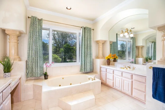 a spacious bathroom with a tub double sink and mirror