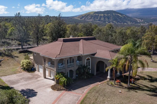 a aerial view of a house with a yard and mountain view in back