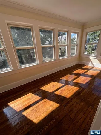 a view of an empty room with wooden floor and windows