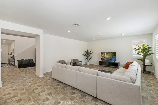 a living room with furniture a flat screen tv and a potted plant