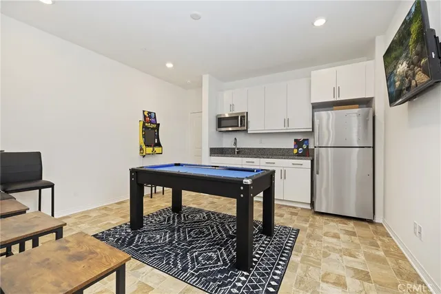 a kitchen with stainless steel appliances granite countertop a refrigerator a stove a sink a dining table and chairs with wooden floor