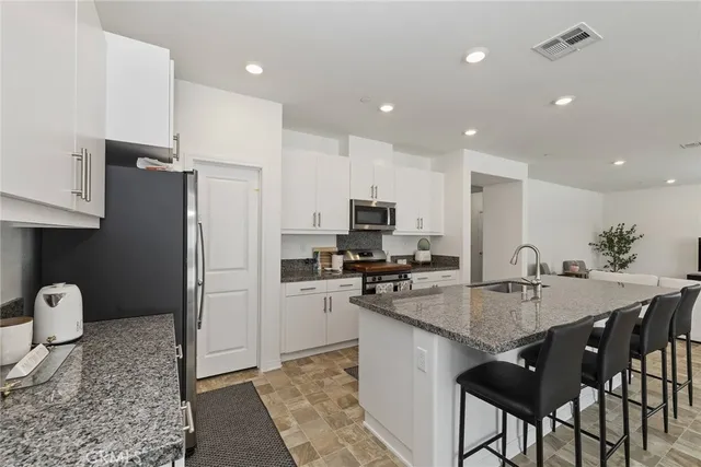 a kitchen with stainless steel appliances granite countertop a stove a refrigerator a sink a stove a dining table and chairs