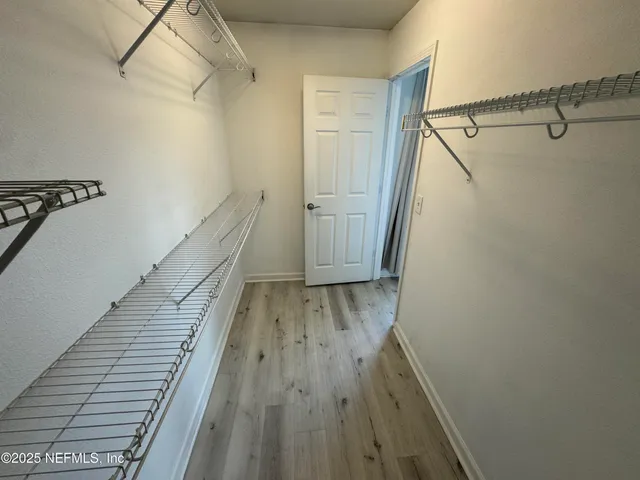 an empty room with wooden floor and a ceiling fan