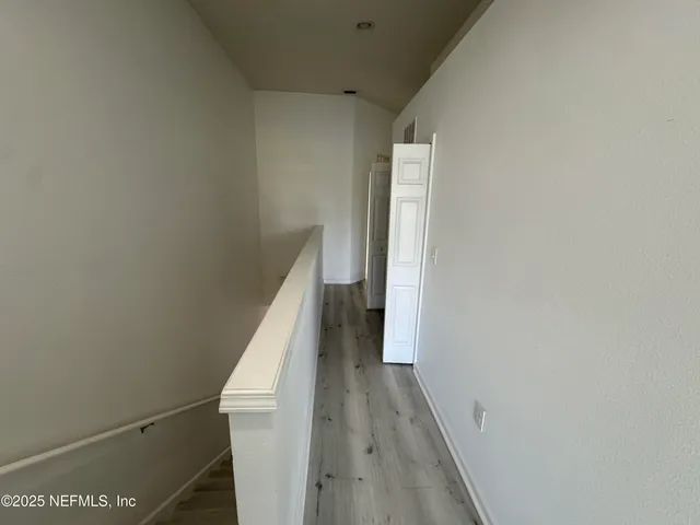 a view of a hallway with wooden floor and entryway