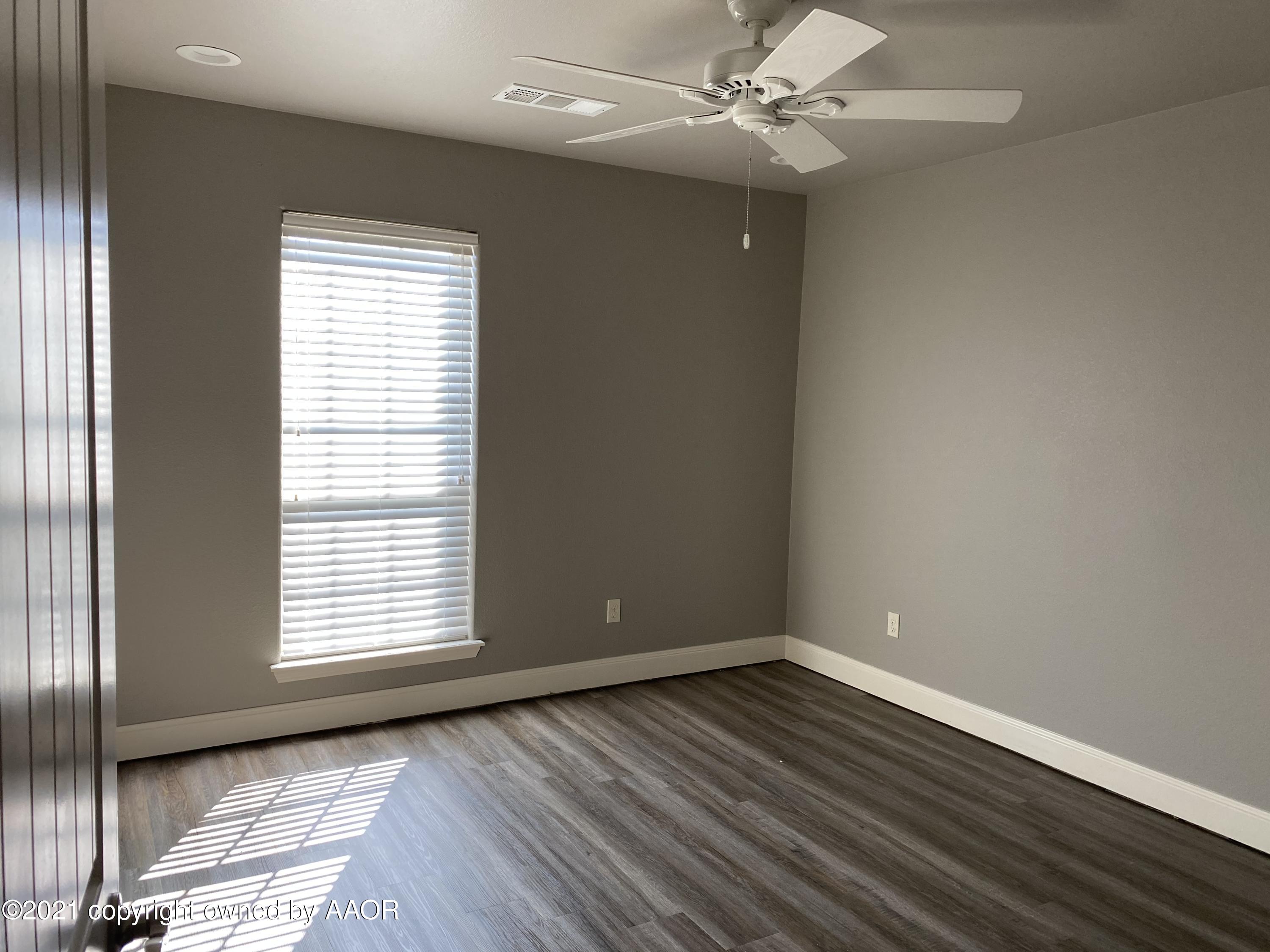 7304 Jacksonhole Drive Amarillo, TX 79118 - Photo 11 of 14 an empty room with wooden floor chandelier fan and windows