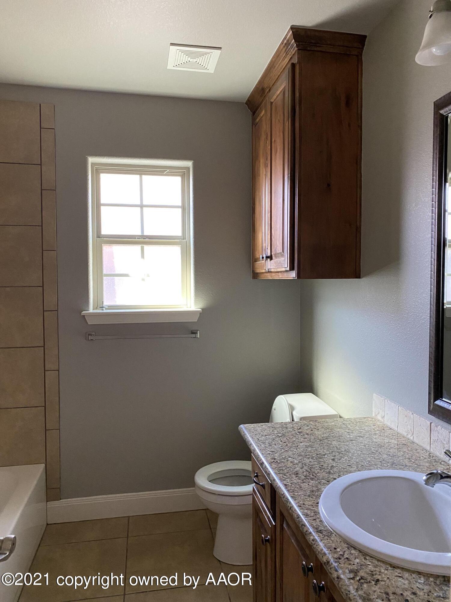 7304 Jacksonhole Drive Amarillo, TX 79118 - Photo 12 of 14 a bathroom with a granite countertop sink a toilet and mirror