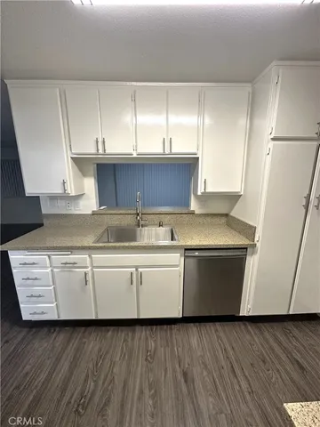 a white kitchen with wooden floors and white stainless steel appliances