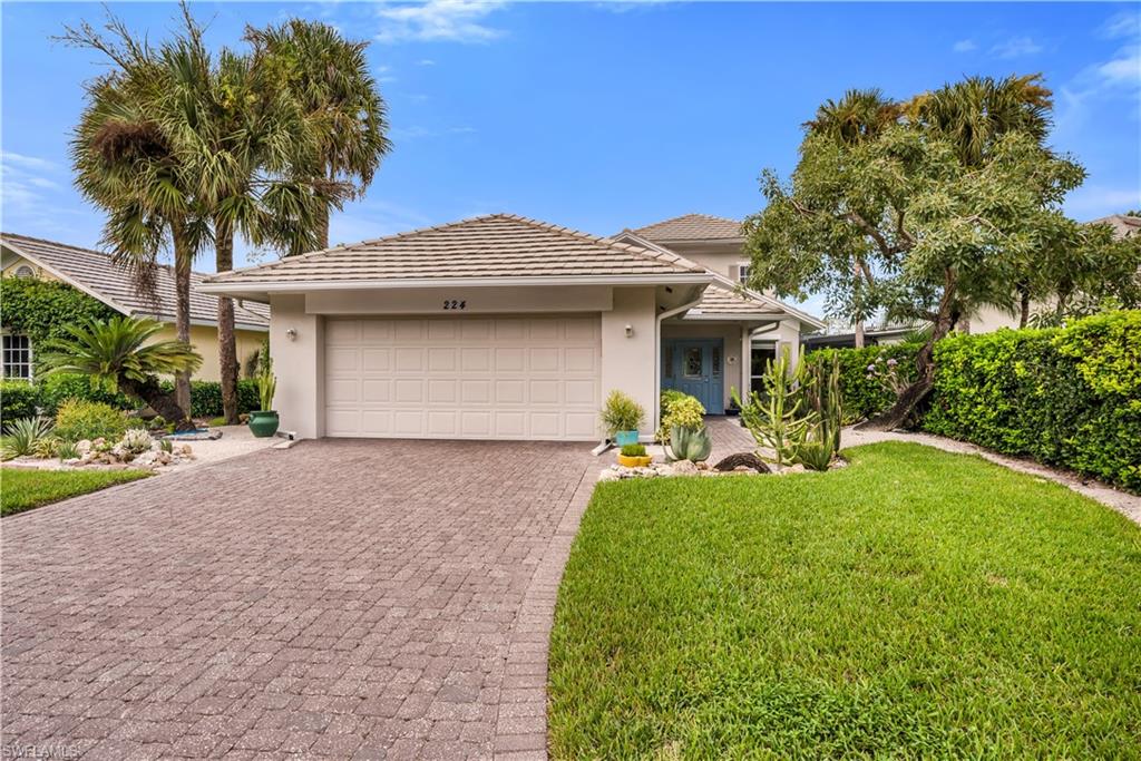 224 Edgemere Way South Naples, FL 34105 - Photo 2 of 35 View of front of house featuring stucco siding, decorative driveway, a front lawn, and a garage
