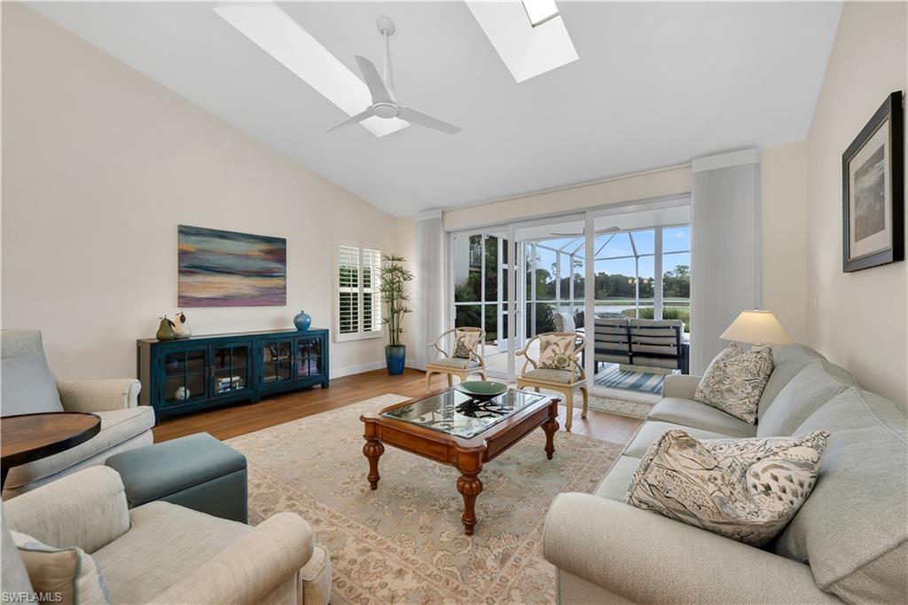 224 Edgemere Way South Naples, FL 34105 - Photo 3 of 35 Living area with wood finished floors, a sunroom, ceiling fan, a skylight, and high vaulted ceiling