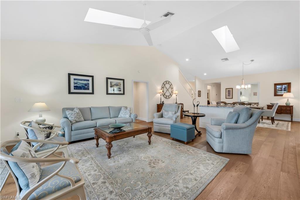 224 Edgemere Way South Naples, FL 34105 - Photo 4 of 35 Living room with a chandelier, a skylight, light wood-style floors, ceiling fan, and high vaulted ceiling