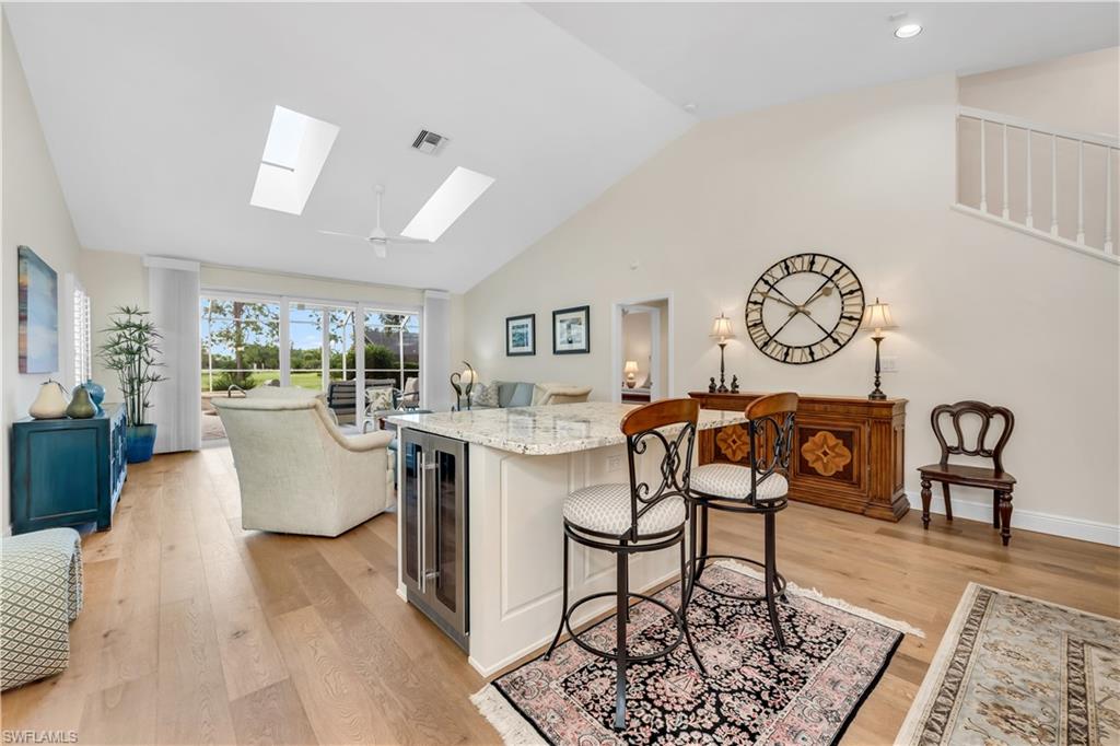 224 Edgemere Way South Naples, FL 34105 - Photo 35 of 35 Family room with light stone countertops, open floor plan, wine cooler, a breakfast bar, and light wood-type flooring