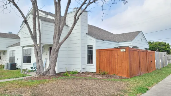 a backyard of a house with plants and large tree