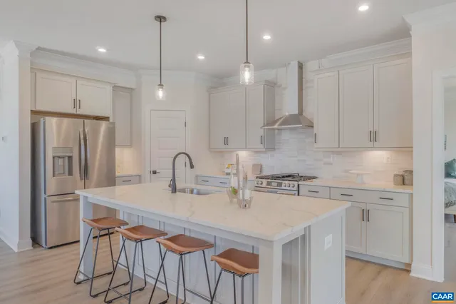 a kitchen with stainless steel appliances granite countertop a sink a stove a refrigerator and island with wooden floor