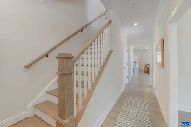 a view of staircase with lots of frames on wall and wooden floor