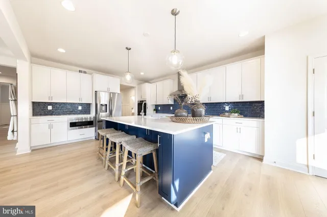 a open kitchen with stainless steel appliances granite countertop a stove a sink a refrigerator and white cabinets with wooden floor