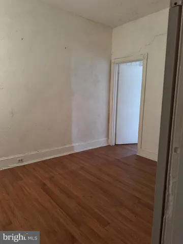 a view of an empty room with wooden floor and closet