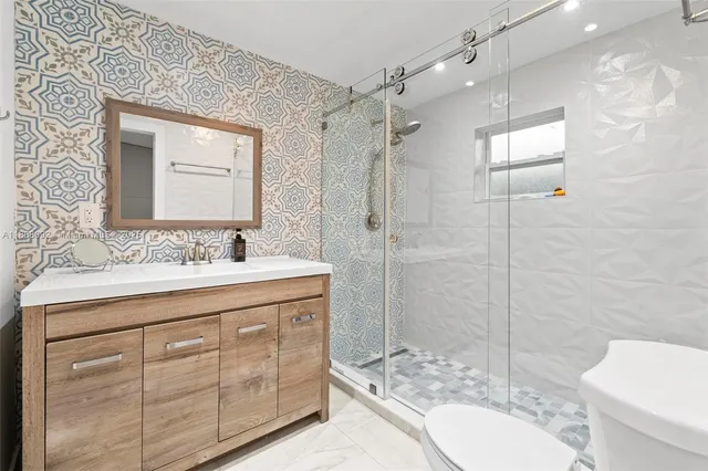 a bathroom with a granite countertop sink toilet mirror and shower