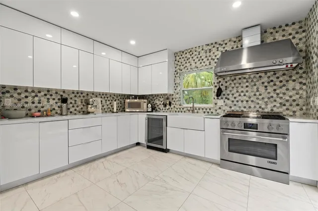 a kitchen with stainless steel appliances a stove a sink and white cabinets