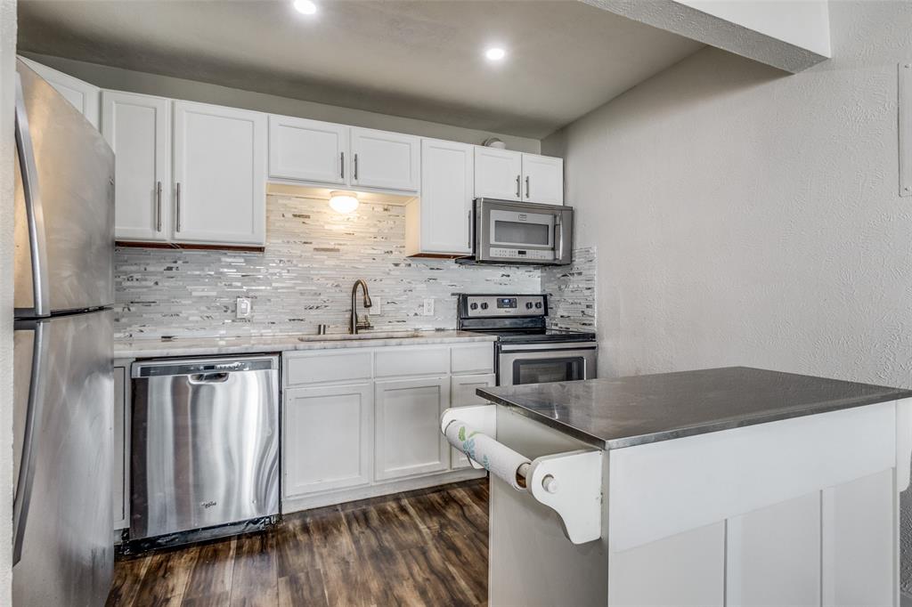 4347 Dickason Avenue, Unit 110 Dallas, TX 75219 - Photo 12 of 24 a kitchen with stainless steel appliances white cabinets a sink a stove a microwave and cabinetry