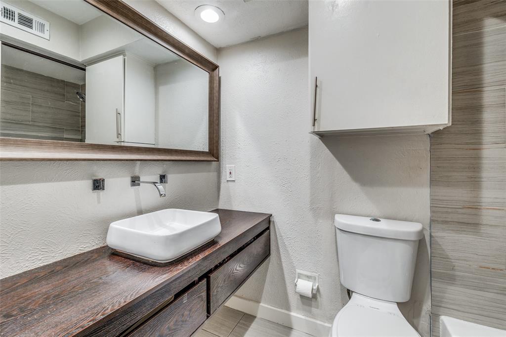 4347 Dickason Avenue, Unit 110 Dallas, TX 75219 - Photo 22 of 24 a bathroom with a sink a toilet and mirror