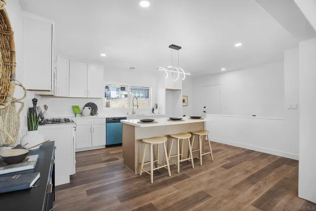 a kitchen with a table chairs a sink dishwasher stove and cabinets with wooden floor