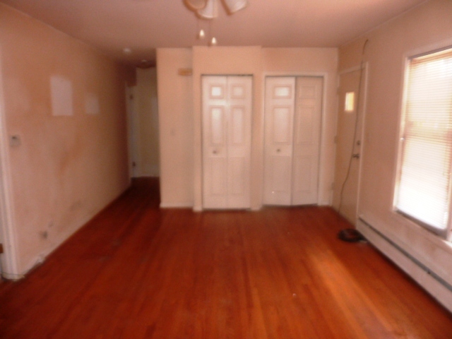 6733 West Irving Park Road, Unit 2C Chicago, IL 60634 - Photo 5 of 10 an empty room with wooden floor and windows